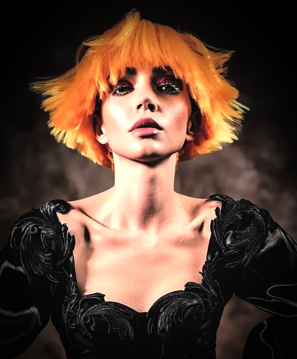 Vibrant orange spiky textured hair photographed against a dark studio background