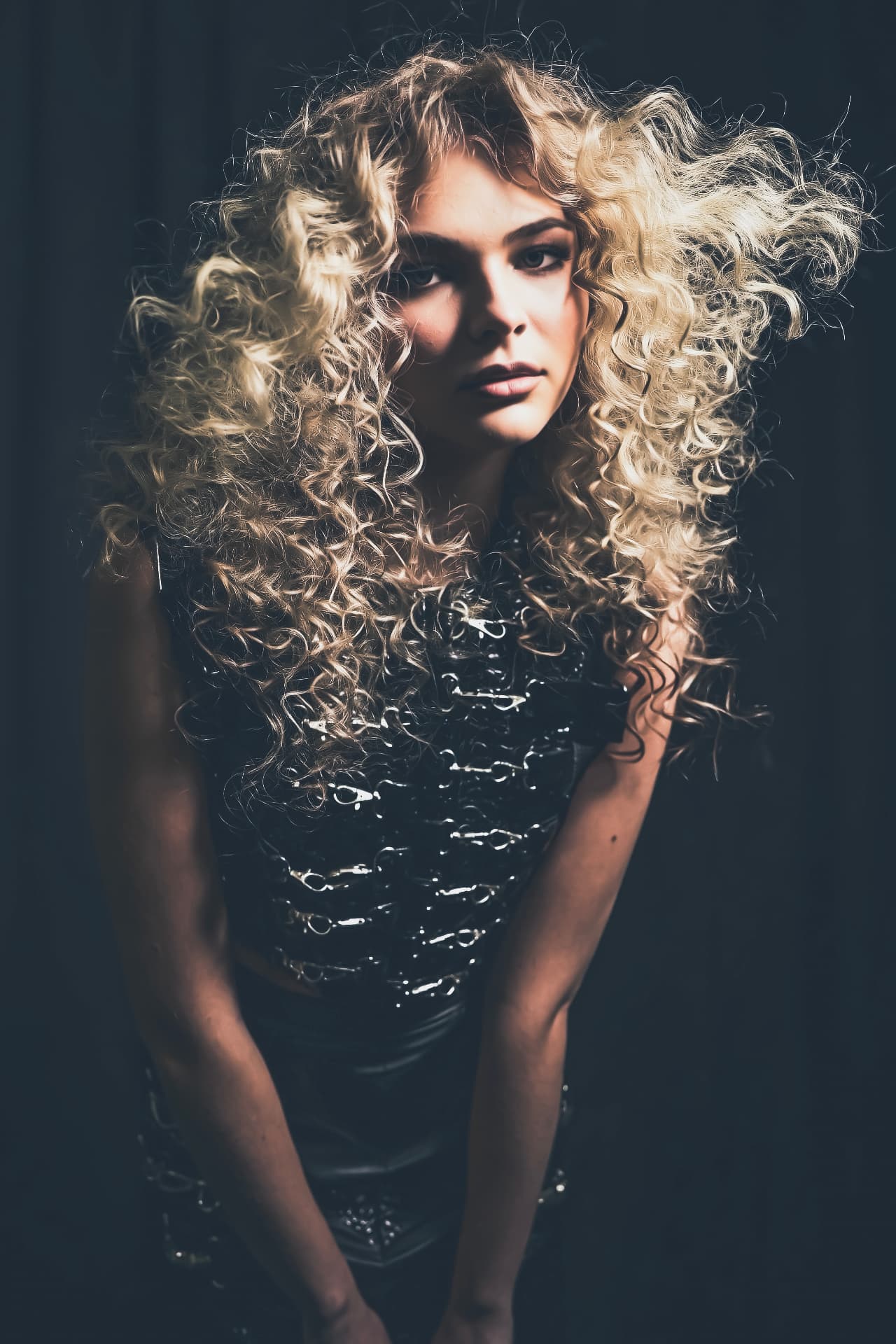 Voluminous curled blonde hair photographed in dark studio light